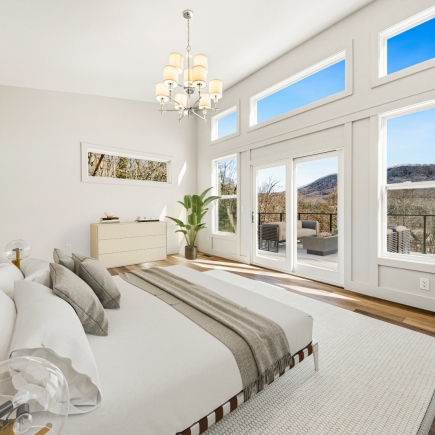 Primary bedroom with chandelier, dresser, and sliding door to the deck