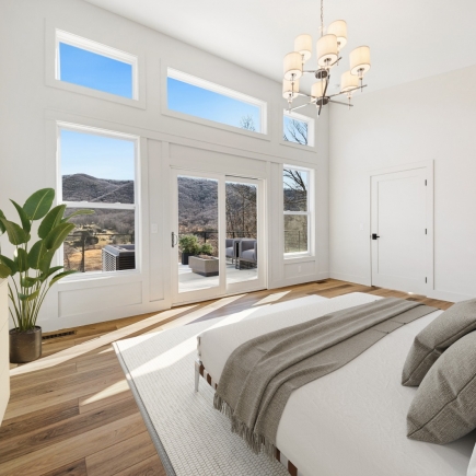 Primary bedroom with vaulted ceiling, mountain-view windows, and deck access