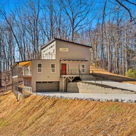 Skyline Ridge House — front exterior on wooded hillside with attached garage and wraparound deck